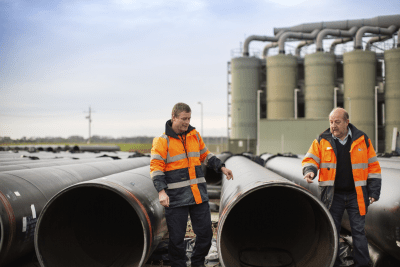 Photo of two workers from Melbourne Water examining a water pipe