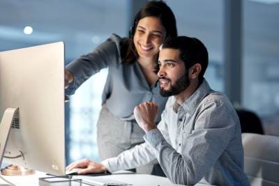 Photo of two office workers looking at a computer screen