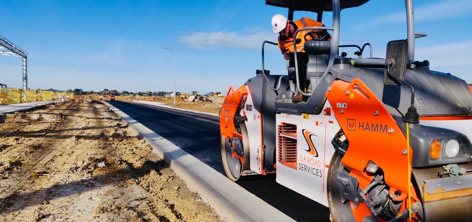 Image of a construction worker in a roller machine finishing off a newly made road.